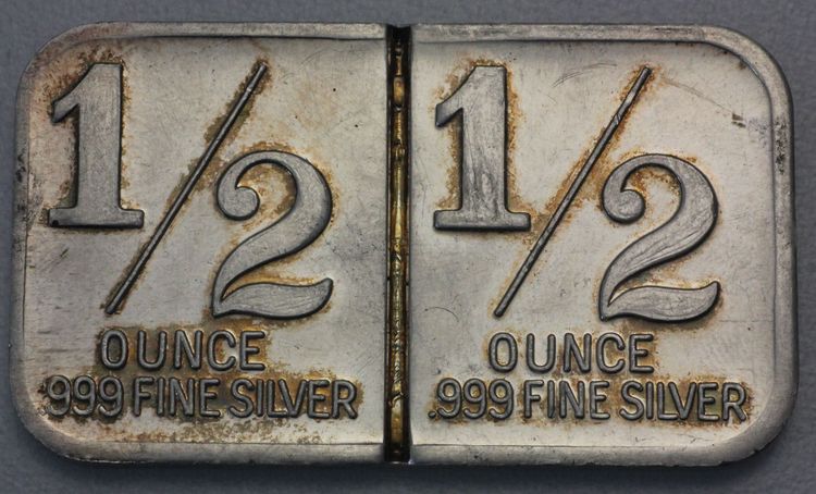 1oz Silberbarren International Trade Unit Rückseite mit Kennzeichnung wo sich der Barren mit Werkzeug (Meißel, Axt, Säge) in 2x0,5oz teilen läßt.